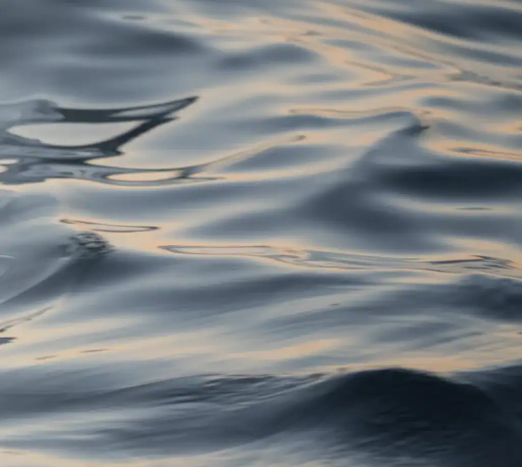 Sanfte Wellenbewegung auf einer Wasseroberfläche bei Sonnenuntergang – Symbol für emotionale Harmonie und vertiefende Feng Shui Analyse.